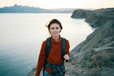 Portrait of smiling young woman standing at sea shore