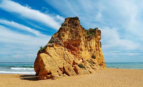 Rock formation on beach against sky