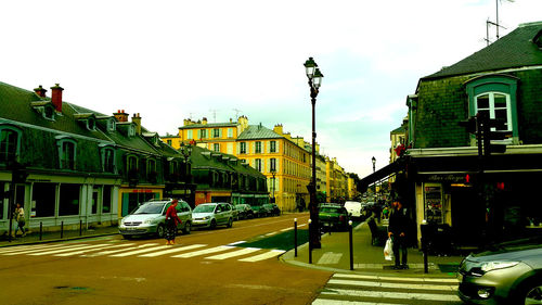 Cars on city street against sky