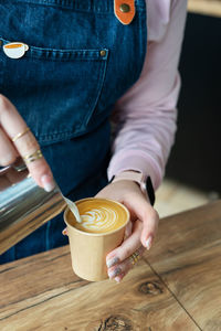 The process of making a barista cappuccino with a beautiful pattern on the foam in an craft glass