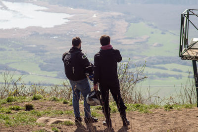 Rear view of men standing on land against sky