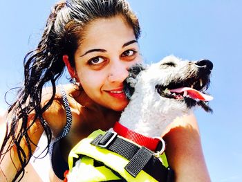 Portrait of young woman with dog against clear blue sky