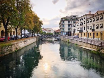 Canal amidst buildings in city against sky