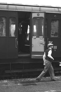 Man standing by train at railroad station platform