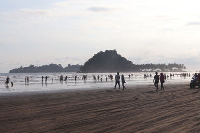 People at beach against sky