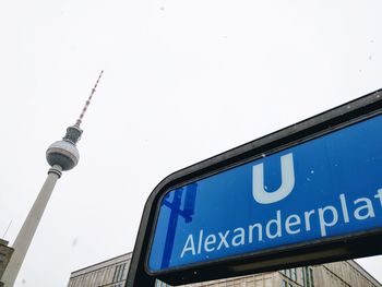 Low angle view of road sign by fernsehturm against clear sky