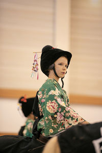 Young woman looking away while sitting on horse