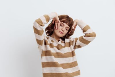 Portrait of young woman standing against white background