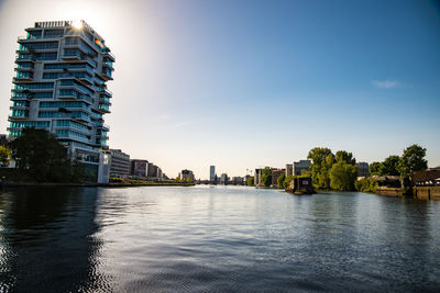 Buildings by river against sky in city