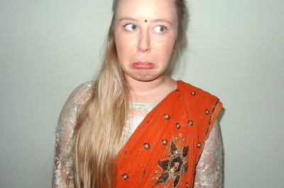 Midsection of woman in sari making face against white background