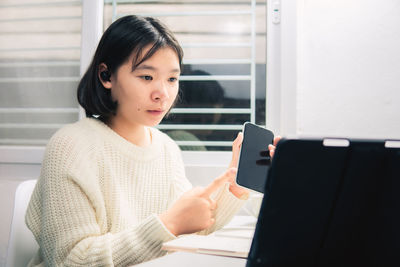 Young woman looking through mobile phone at home