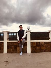 Full length portrait of young man standing against sky