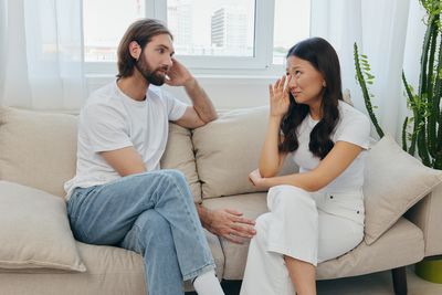 Couple using phone while sitting on sofa at home