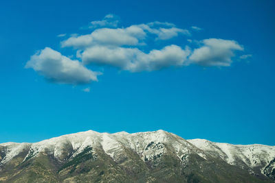 Low angle view of snowcapped mountains against blue sky