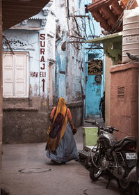 Rear view of woman sitting on street against buildings in city
