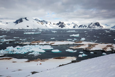 Scenic view of icebergs and snowcapped mountains against sky