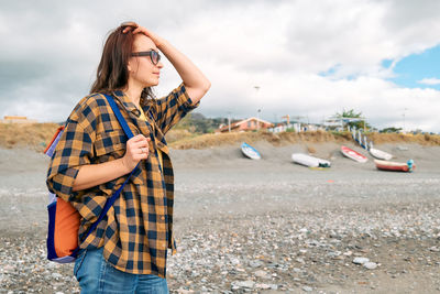 Woman in warm plaid shirt walking by sea on winter beach. traveling. wellbeing and harmony concept.