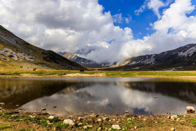 Scenic view of lake by mountains against sky