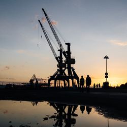 Silhouette people on boat in city against sky during sunset