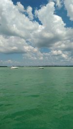 Boats in sea against cloudy sky