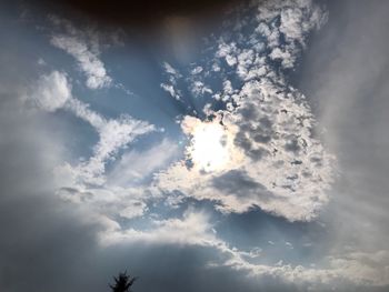 Low angle view of sunlight streaming through clouds