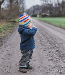 Side view of girl standing on dirt road