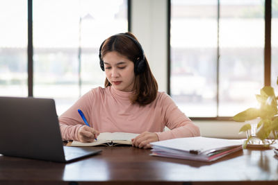 Young woman writing in book at classroom