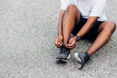 Low section of man tying shoelace