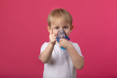 Portrait of cute boy drinking against red background