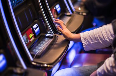 Midsection of woman sitting by slot machine