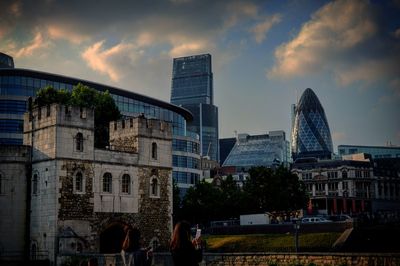 Buildings in city against cloudy sky