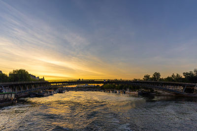 Bridge over river against sky during sunset