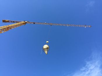 Low angle view of crane against clear blue sky