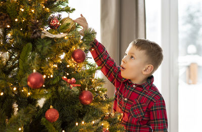 Cute girl decorating christmas tree at home