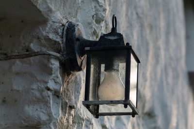 Close-up of old lamp hanging against wall