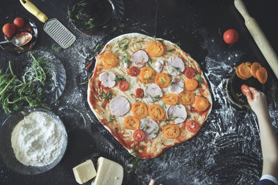 Child and an adult prepare pizza dinner, hands add sausage and tomatoes, copy space and lifestyle