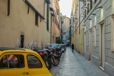 Vehicles parked in alley amidst buildings