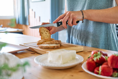 Woman making summer strawberry sandwich. female hands cutting bread for toast.