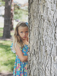 Portrait of cute girl standing on tree trunk