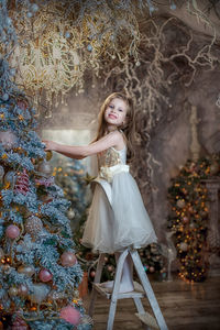 Portrait of young woman standing against tree