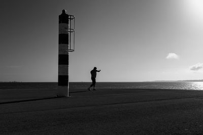 Silhouette man by sea against sky