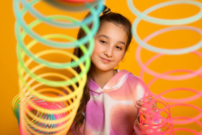 Teen girl play rainbow slinky toy on color background