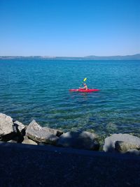 Man kayaking in sea against clear blue sky