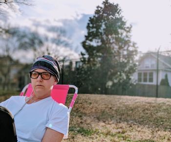 Portrait of woman wearing sunglasses standing against trees