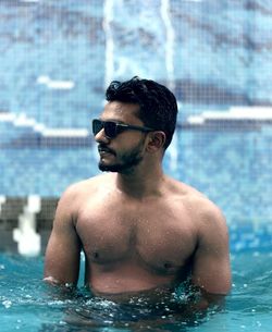 Shirtless man swimming in pool