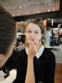 Midsection of beautician applying make-up on woman in spa 