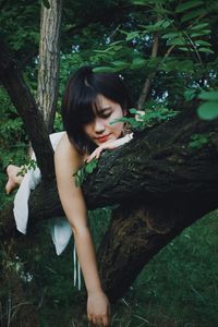 Woman sitting on tree trunk in forest