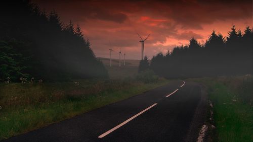 Road passing through field at sunset