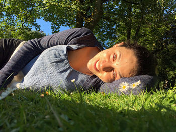 Portrait of young woman lying on grassy field at park