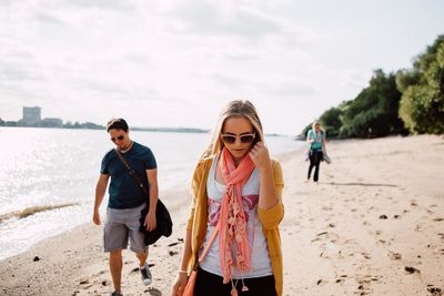 Friends walking at beach against sky